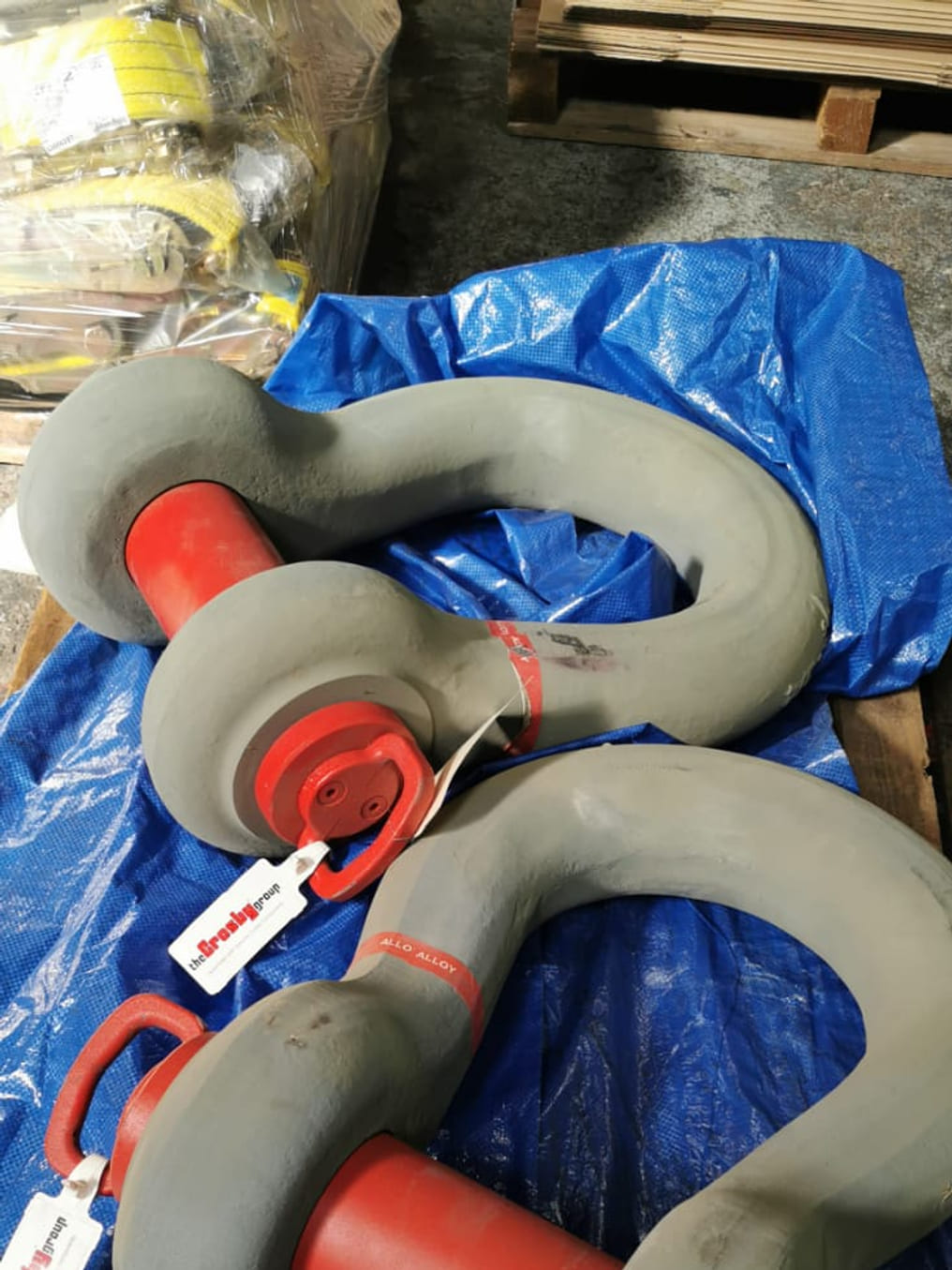 Two large Crosby alloy bow shackles with red-painted pins, stocked on a pallet in the Afrishore Lifting & Rigging hub – the brand-name premium hardware specified for offshore lifting, heavy crane work and dynamic loading.